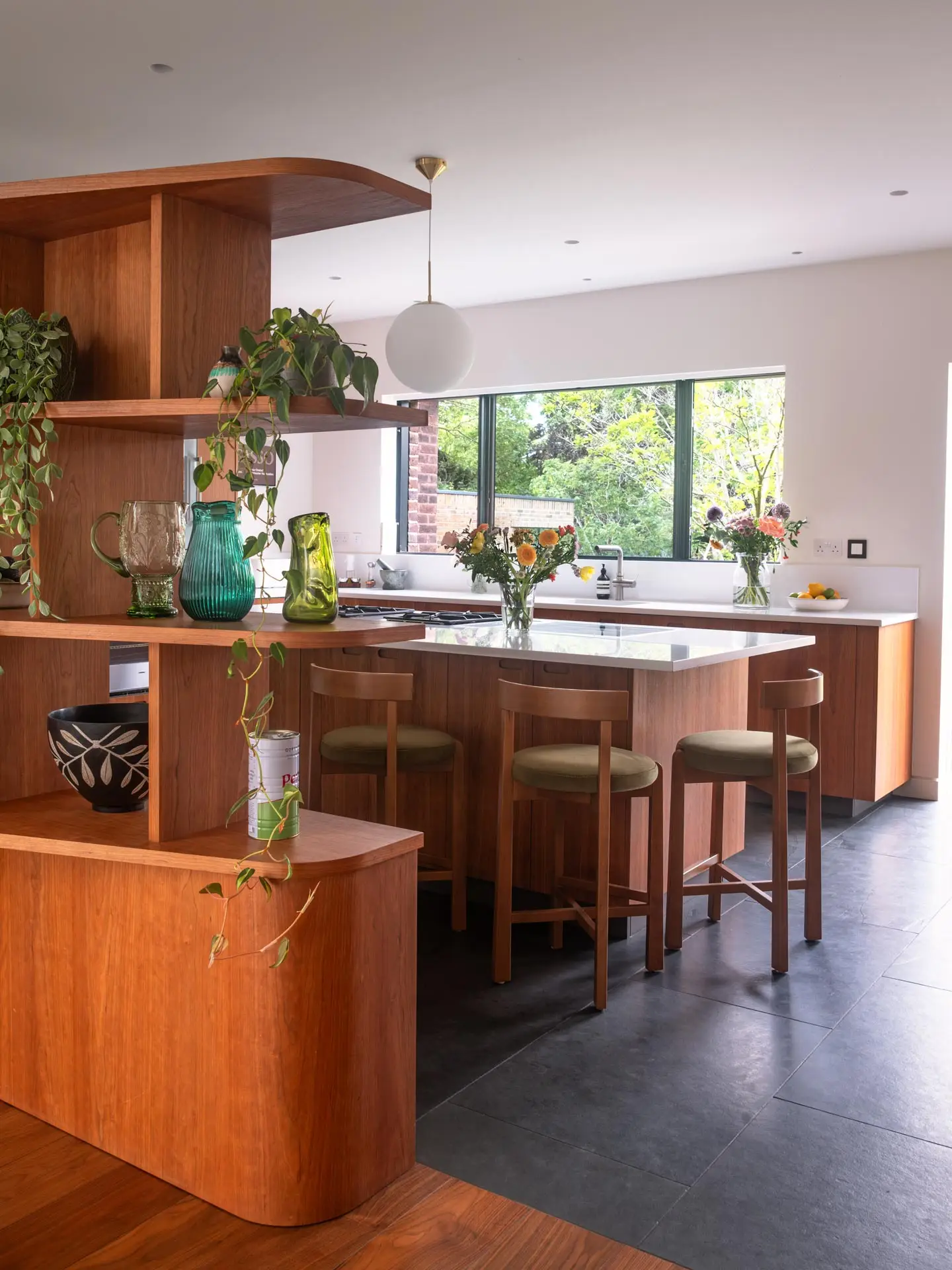 A Pluck kitchen in London with cherry wood custom cabinetry in an open plan home with an island and cooking kit.