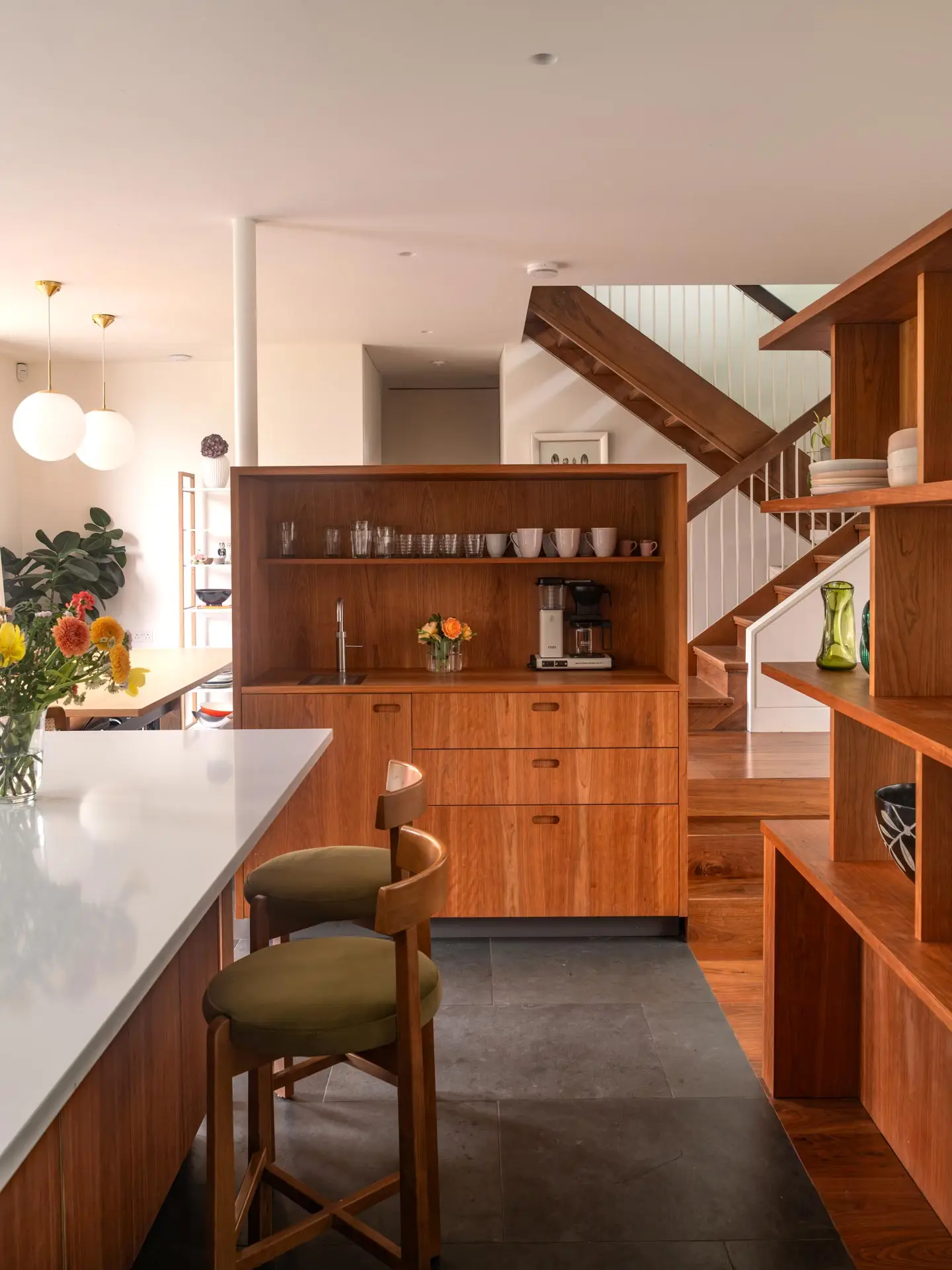 A Pluck kitchen in London with cherry wood custom cabinetry in an open plan home with an island and cooking kit.