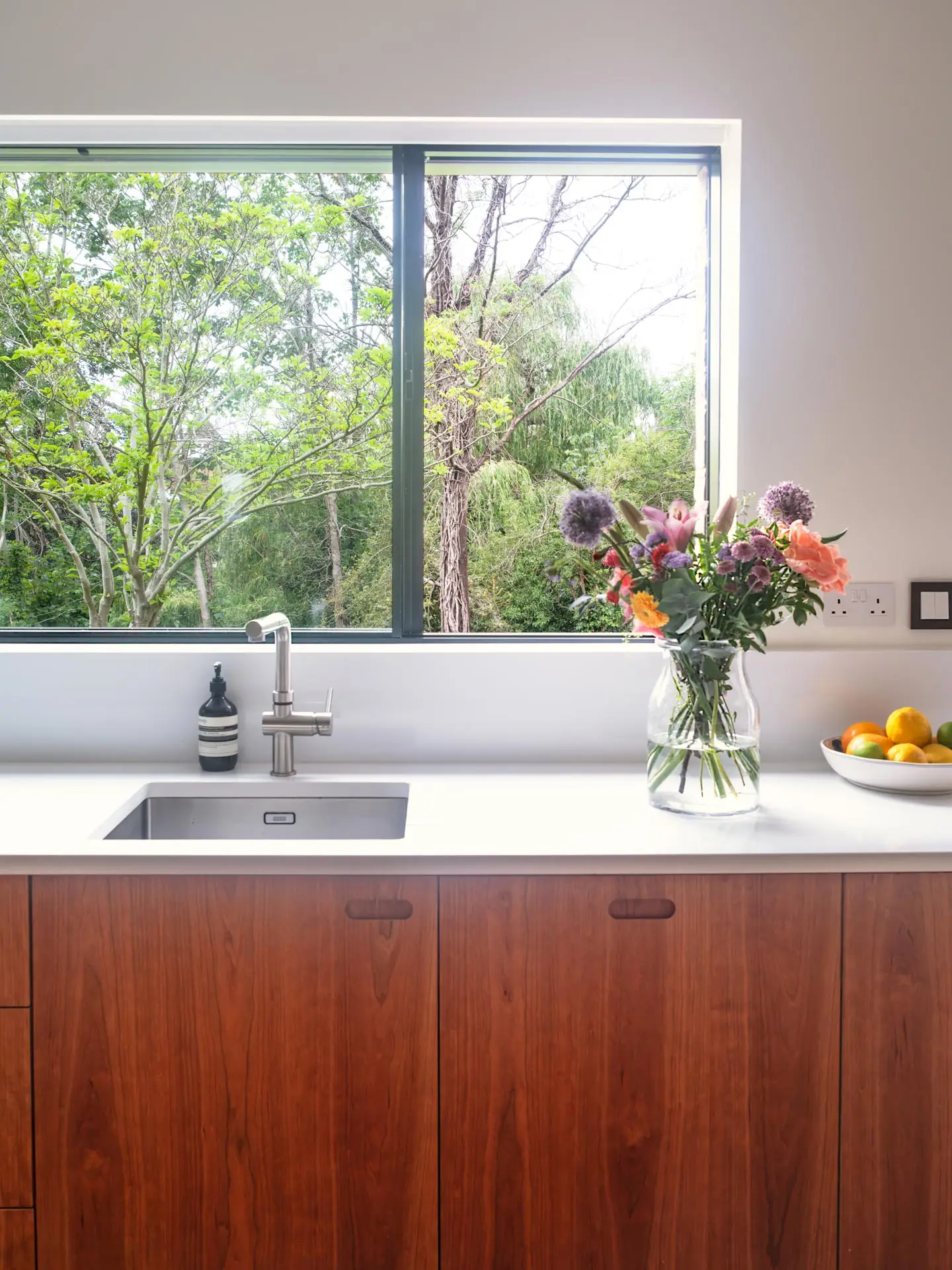 Warm cherry wood Pluck cabinetry including an island in an open plan London family home.