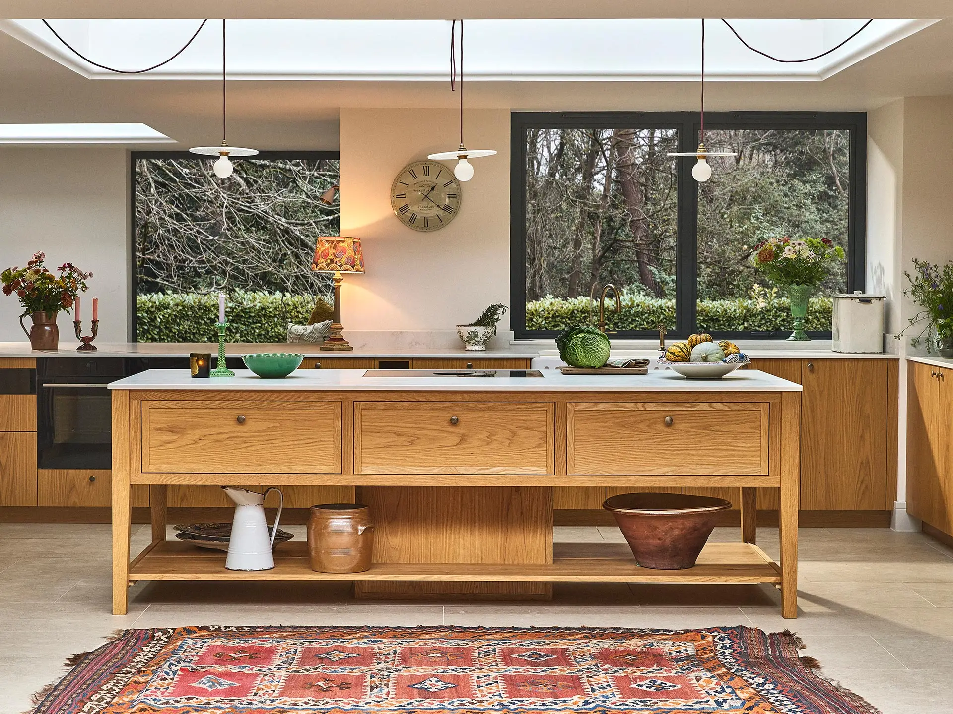 A large open plan kitchen with oak cabinets and a large central cook's table in a Surrey countryside family home.